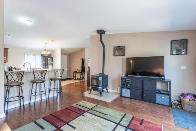 35600 Rock Creek Rd, Shingletown, CA 96088 - living room featuring baseboards, a chandelier, wood finished floors, and a wood stove
