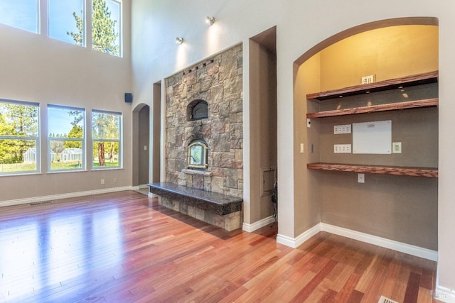 35600 Rock Creek Rd, Shingletown, CA 96088 - unfurnished living room featuring visible vents, arched walkways, wood finished floors, and a healthy amount of sunlight