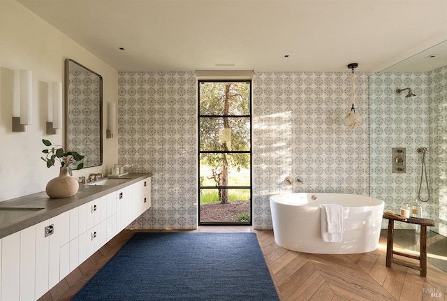 bathroom with double vanity, a freestanding bath, plenty of natural light, and a sink