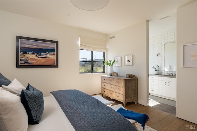 bedroom with hardwood / wood-style flooring and ensuite bath