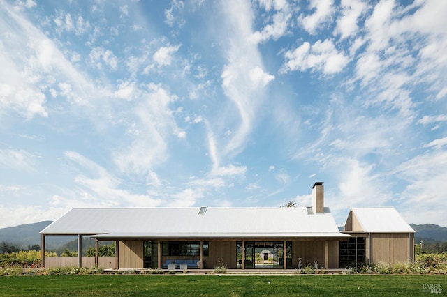 back of property with a yard, a chimney, and a mountain view