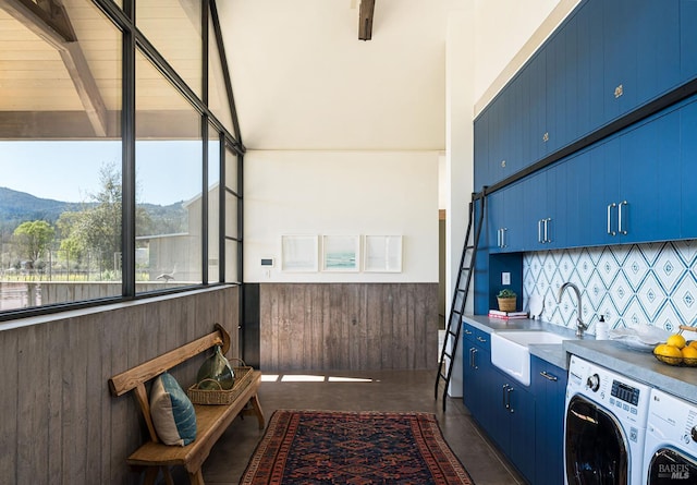 washroom featuring laundry area, wooden walls, a mountain view, washing machine and clothes dryer, and a sink