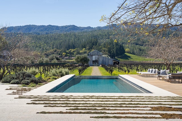 pool with an outbuilding, a wooded view, and a mountain view