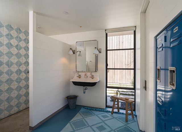 full bathroom featuring tile walls, a tile shower, and a sink