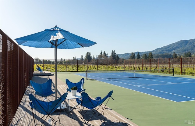 view of sport court featuring a mountain view, community basketball court, and fence