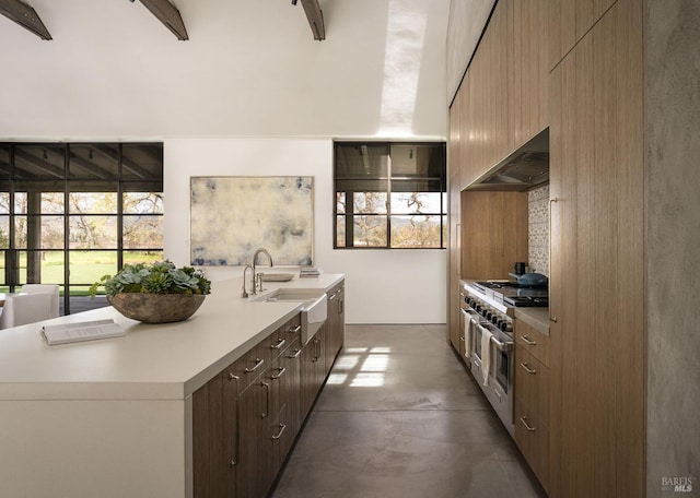 kitchen featuring concrete flooring, a sink, light countertops, range with two ovens, and range hood