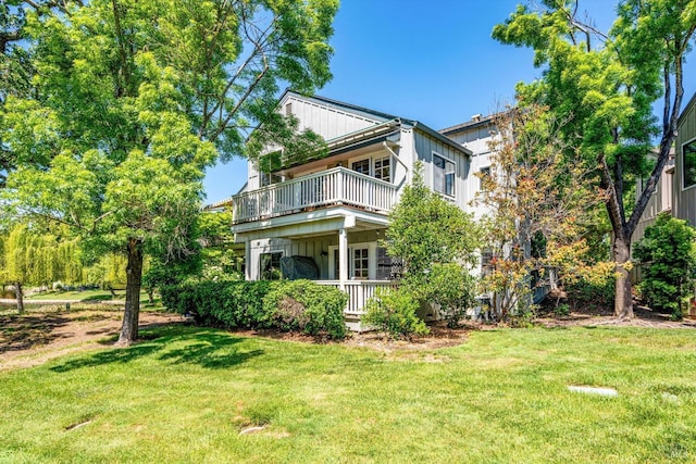 view of side of property featuring a lawn, board and batten siding, and a balcony