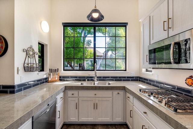 kitchen with white cabinets, a sink, light countertops, stainless steel appliances, and decorative light fixtures
