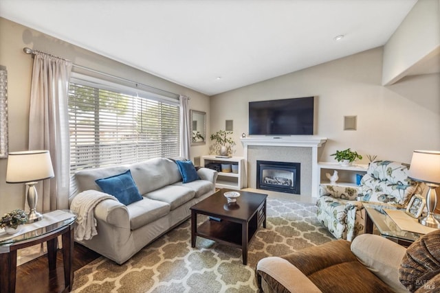 living area featuring lofted ceiling and a glass covered fireplace