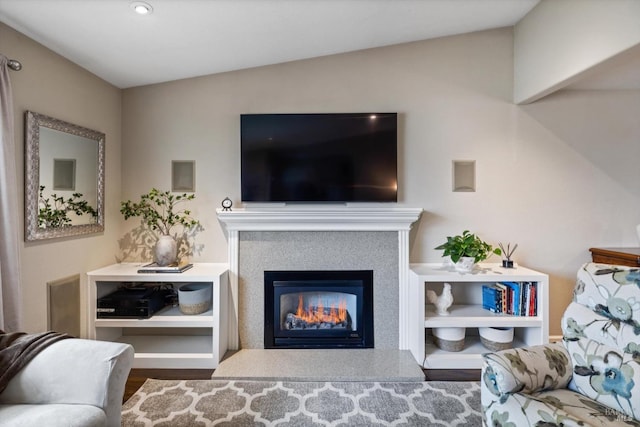 living room featuring vaulted ceiling, wood finished floors, and a glass covered fireplace