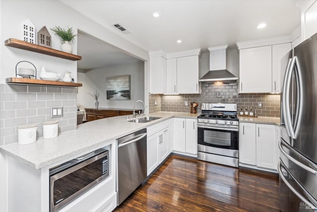 kitchen featuring a sink, visible vents, wall chimney range hood, appliances with stainless steel finishes, and decorative backsplash
