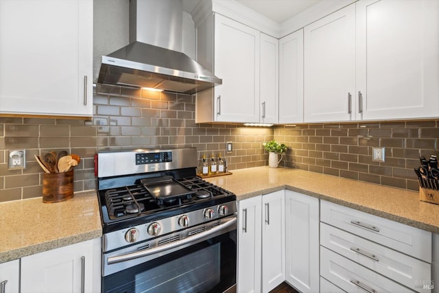 kitchen with light stone countertops, gas stove, wall chimney range hood, and white cabinets