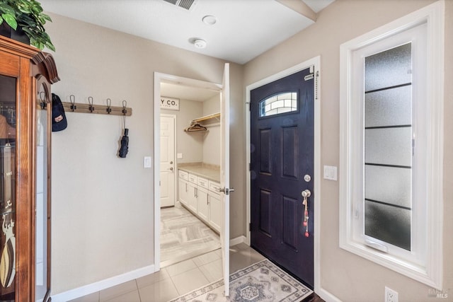 foyer featuring baseboards and light tile patterned flooring