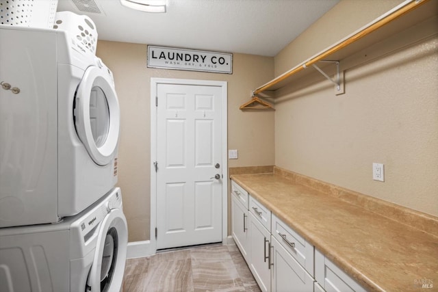 laundry room featuring stacked washer / dryer, cabinet space, and visible vents