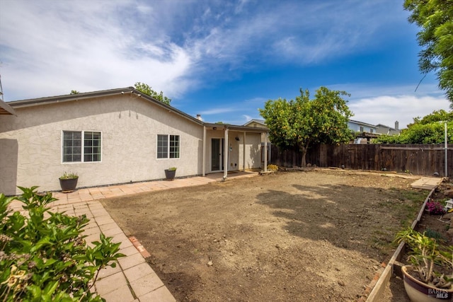 back of house featuring a fenced backyard, a patio, and stucco siding