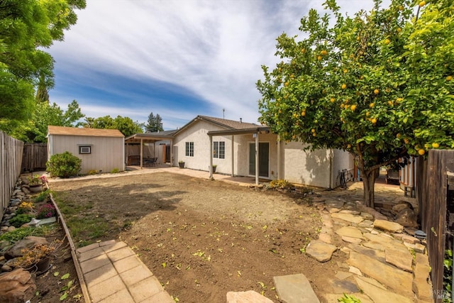 back of property with a patio area, stucco siding, a shed, an outbuilding, and a fenced backyard