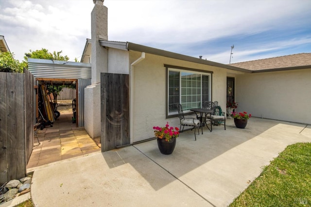 rear view of property featuring stucco siding, a chimney, fence, and a patio area