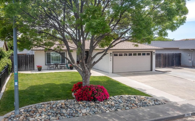 ranch-style house with fence, concrete driveway, a garage, stucco siding, and a front yard