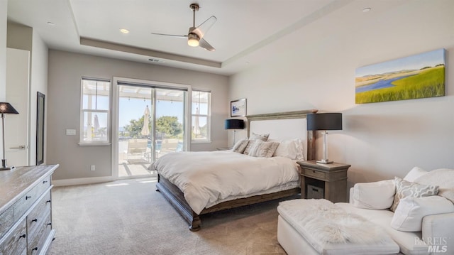 bedroom with ceiling fan, access to exterior, baseboards, light carpet, and a tray ceiling