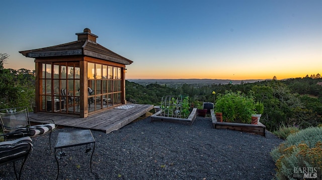 patio terrace at dusk featuring a gazebo and a vegetable garden