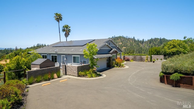 craftsman inspired home featuring fence, a gate, roof mounted solar panels, and a garage
