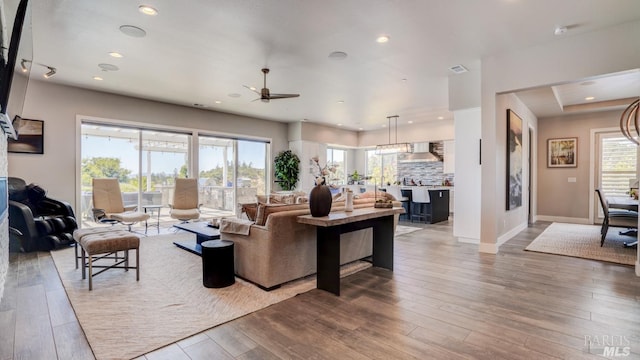 living area featuring light wood-type flooring, a ceiling fan, a healthy amount of sunlight, and recessed lighting