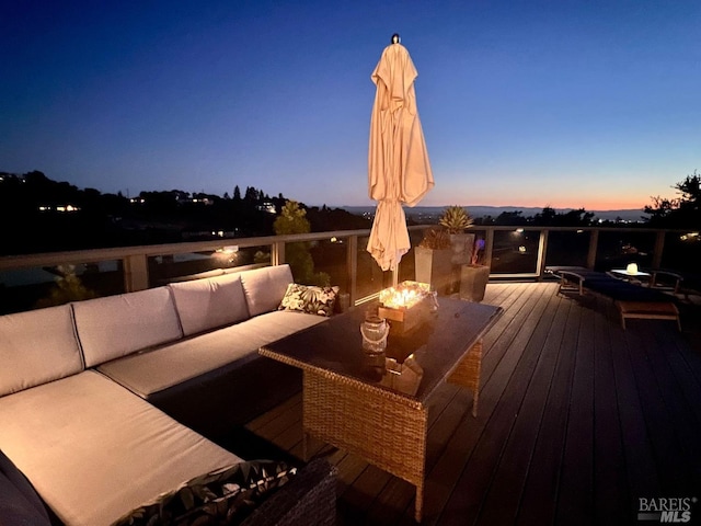 deck at dusk with an outdoor living space with a fire pit