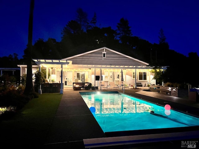 pool at night with a patio, an outdoor living space, an outdoor pool, and a pergola