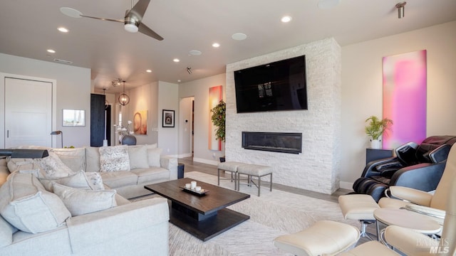 living area with recessed lighting, a ceiling fan, wood finished floors, and a stone fireplace