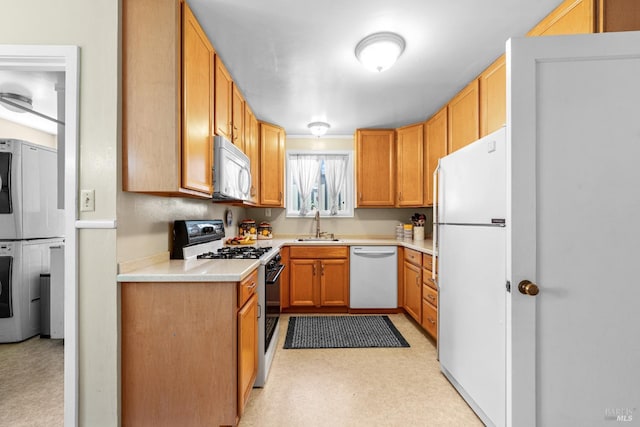 kitchen with a sink, light countertops, stacked washer and clothes dryer, and white appliances