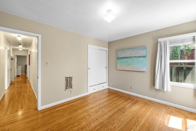 unfurnished bedroom with a closet, baseboards, visible vents, and light wood-type flooring