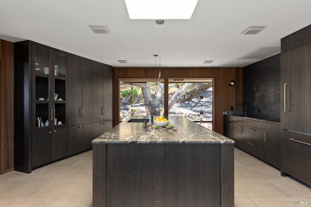 1499 Rockville Rd, Fairfield, CA 94534 - kitchen with a sink, a center island with sink, dark stone counters, dark brown cabinets, and wood walls