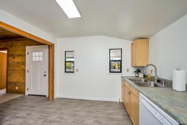 kitchen featuring light brown cabinetry, white dishwasher, wooden walls, a sink, and lofted ceiling