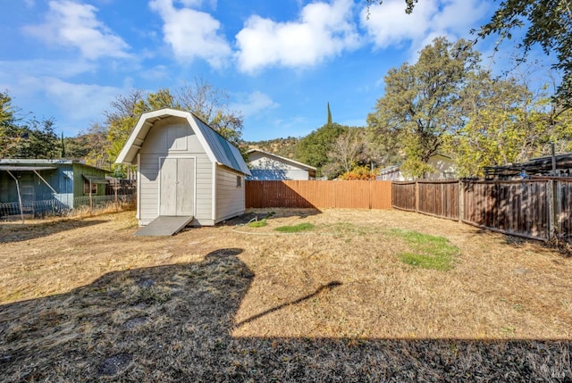view of yard with an outdoor structure, a fenced backyard, and a storage unit