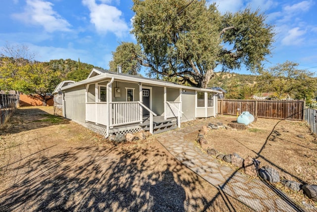 back of house with a fenced backyard and covered porch