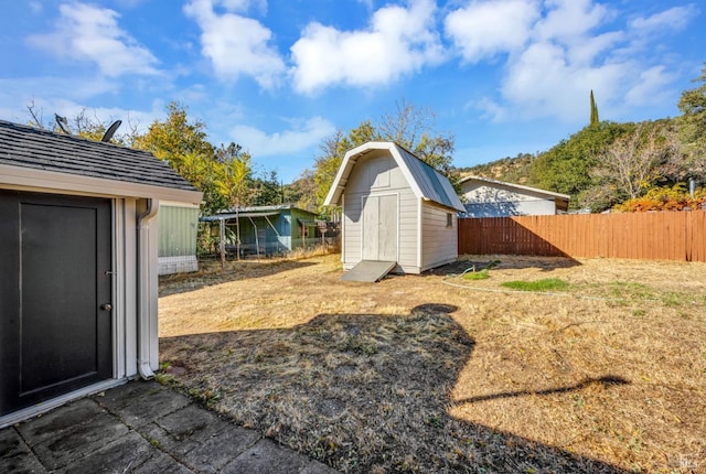 view of yard with fence, a storage unit, and an outdoor structure