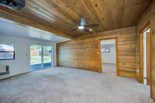 carpeted empty room featuring wooden walls, a ceiling fan, heating unit, and wood ceiling