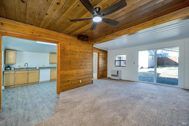 unfurnished living room featuring a sink, wood walls, a ceiling fan, heating unit, and wooden ceiling