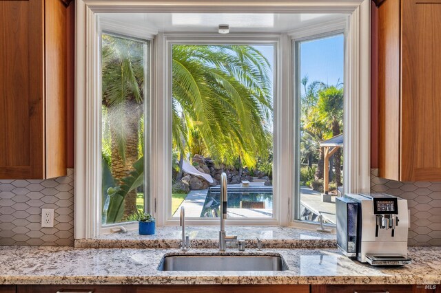 220 Deer Park Ave, San Rafael, CA 94901 - kitchen view of a sink, backsplash, light stone counters, and brown cabinets