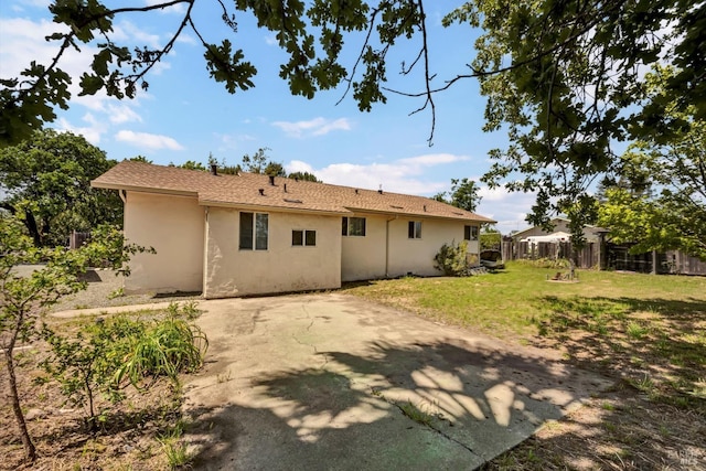 rear view of house with fence, a patio, stucco siding, and a yard