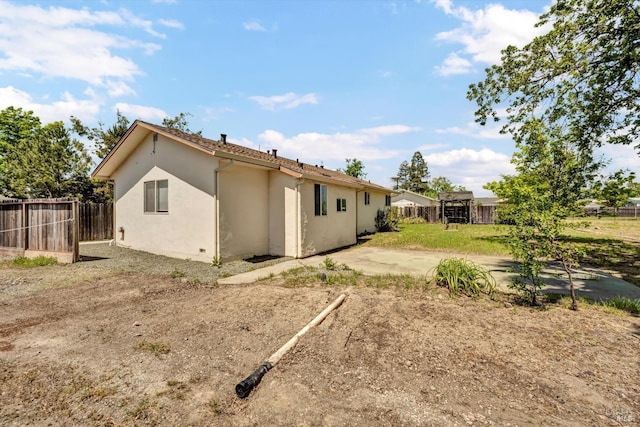 rear view of house with fence, stucco siding, and a patio area