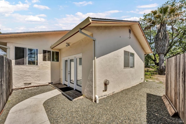 back of house with fence, french doors, and stucco siding