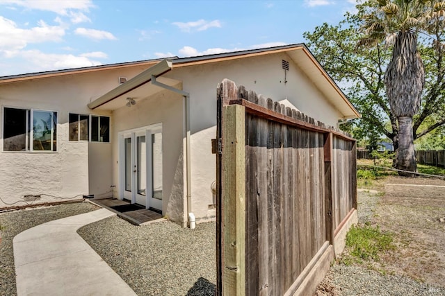 back of property featuring fence, stucco siding, and french doors