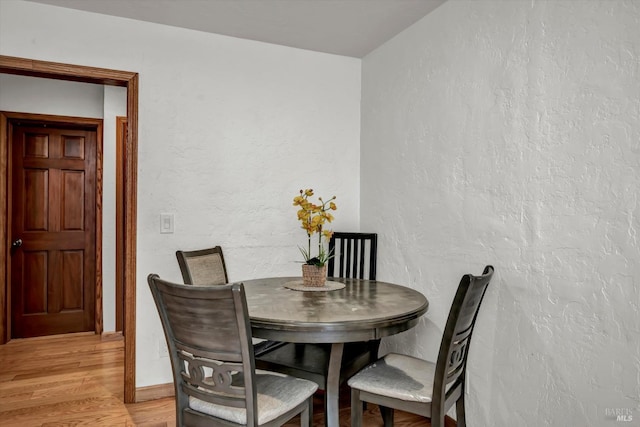 dining space with a textured wall and light wood-style flooring