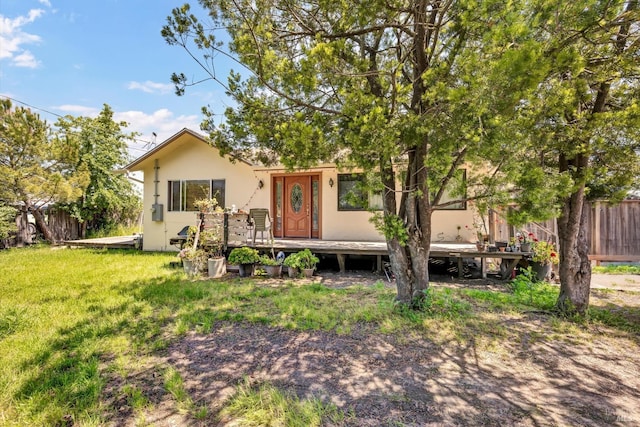 back of property featuring a lawn, a deck, fence, and stucco siding