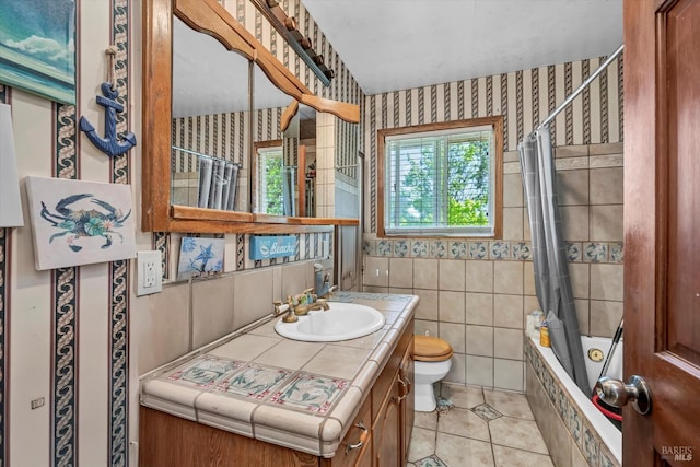 bathroom with vanity, toilet, tile patterned floors, tiled shower / bath, and wallpapered walls