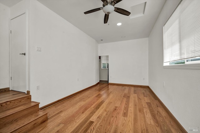 unfurnished room with baseboards, a ceiling fan, light wood finished floors, and stairs