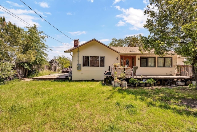 back of house featuring fence, a deck, stucco siding, a chimney, and a yard
