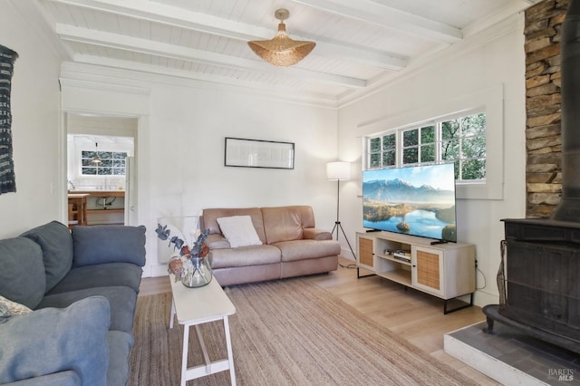 living room featuring beam ceiling, wooden ceiling, wood finished floors, and a wood stove