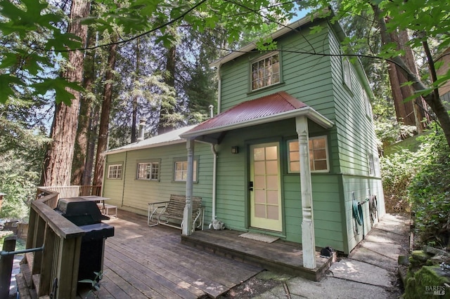 rear view of property featuring a wooden deck and metal roof